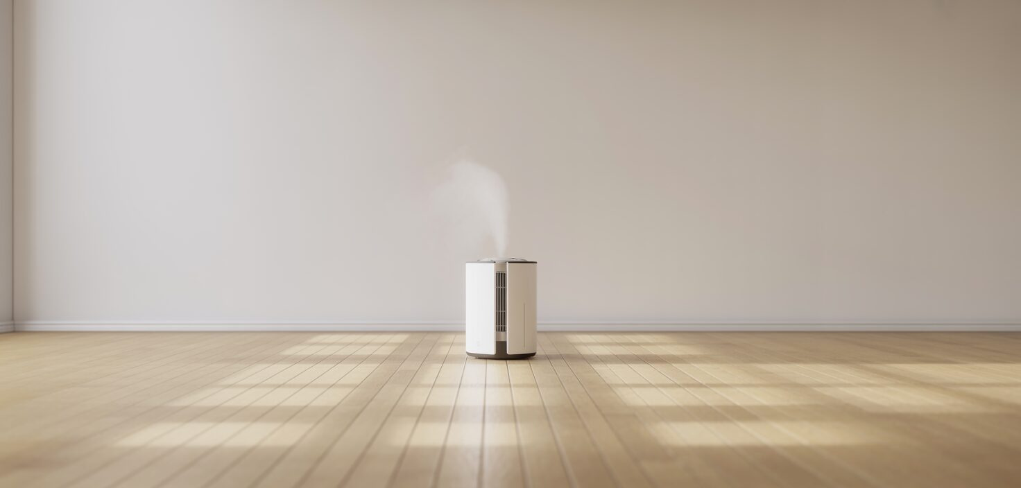 Ett minimalistiskt interiörfoto som visar en luftfuktare på ett trägolv i ett ljust rum.